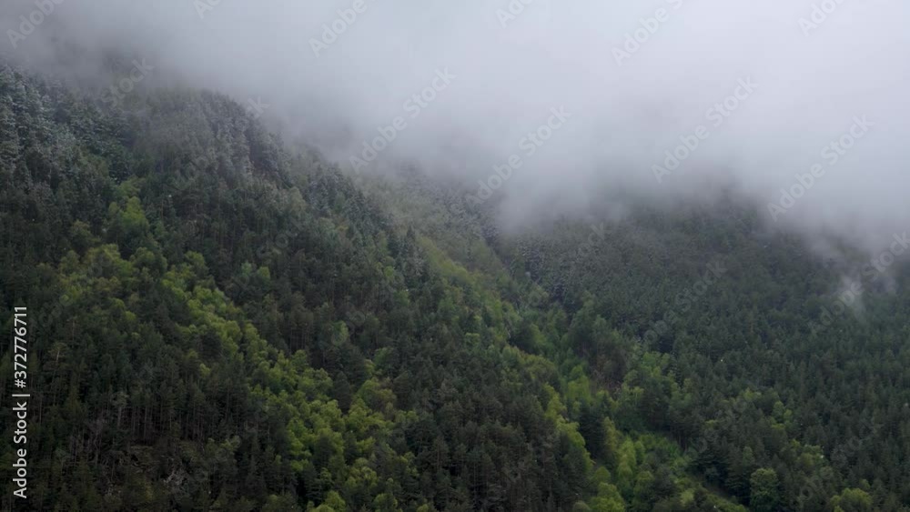 Time lapse steep mountain slopes covered with eternally green forest and powdered with snow on which low clouds flow. 4K cloud movement in the mountains Time lapse steep mountain slopes covered with eternally green forest and powdered with snow on which low clouds flow. 4K cloud movement in the mountains