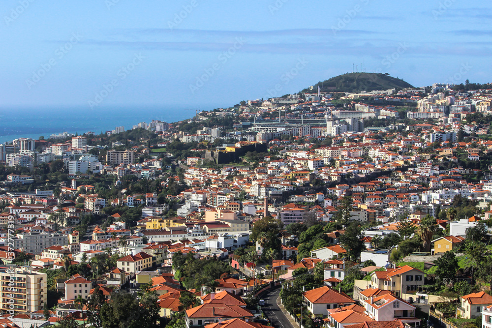 Aerial view of Funchal,the capital of Madeira Island,Portugal,on the coast of Atlantic Ocean. One of Portuguese main tourist attractions.Seafront houses with red roofs,mountain valley and sea.