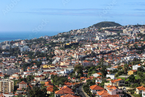 Aerial view of Funchal,the capital of Madeira Island,Portugal,on the coast of Atlantic Ocean. One of Portuguese main tourist attractions.Seafront houses with red roofs,mountain valley and sea. © Eva