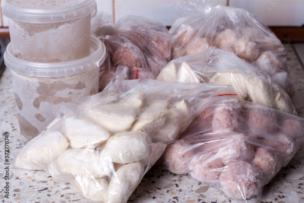 Frozen food (dumplings, meatballs, broth) on the table. Refrigerator with frozen food