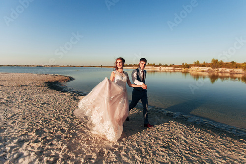 the bride and groom are walking on the beach © Alisa