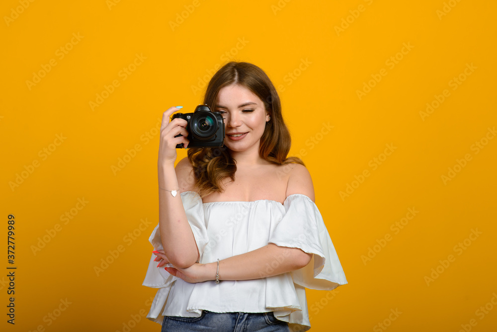 Young female photographer with camera over yellow background Young female photographer with camera over yellow background