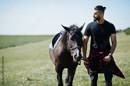 Arab tall beard man wear in black with arabian horse.