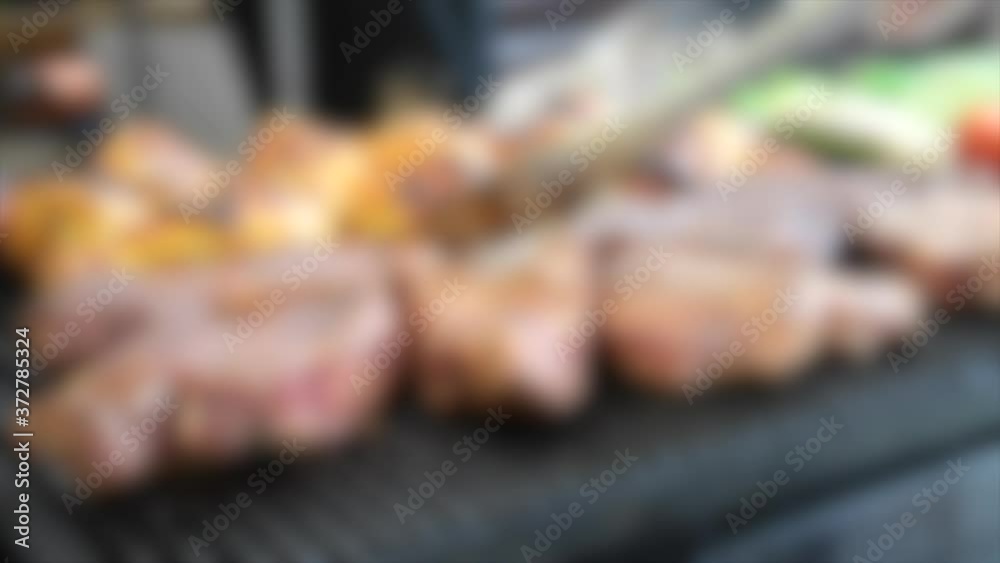 Blurred background. man turns meat steaks and chicken legs on the grill close up