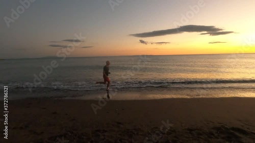 adult caucasian man running on beach at sunset barefoot