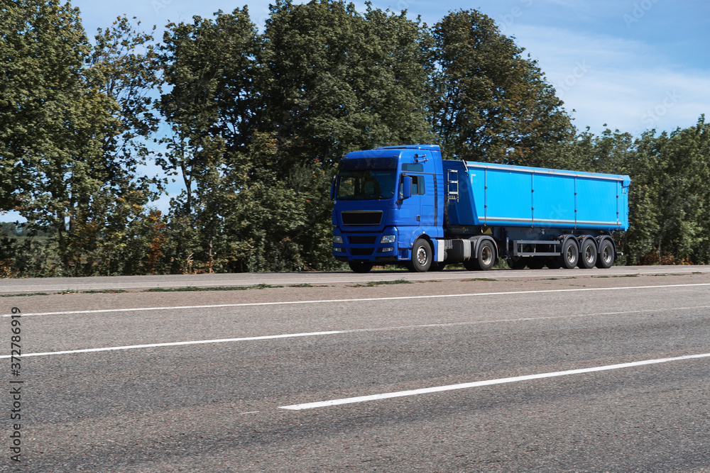 truck on the road, side view, empty space on a blue container - concept of cargo transportation, trucking industry