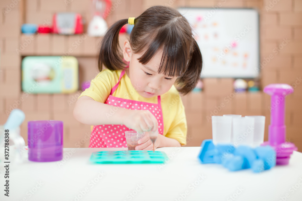 young girl making sweet gems for homeschooling in the kitchen build by cardboard young girl making sweet gems for homeschooling in the kitchen build by cardboard