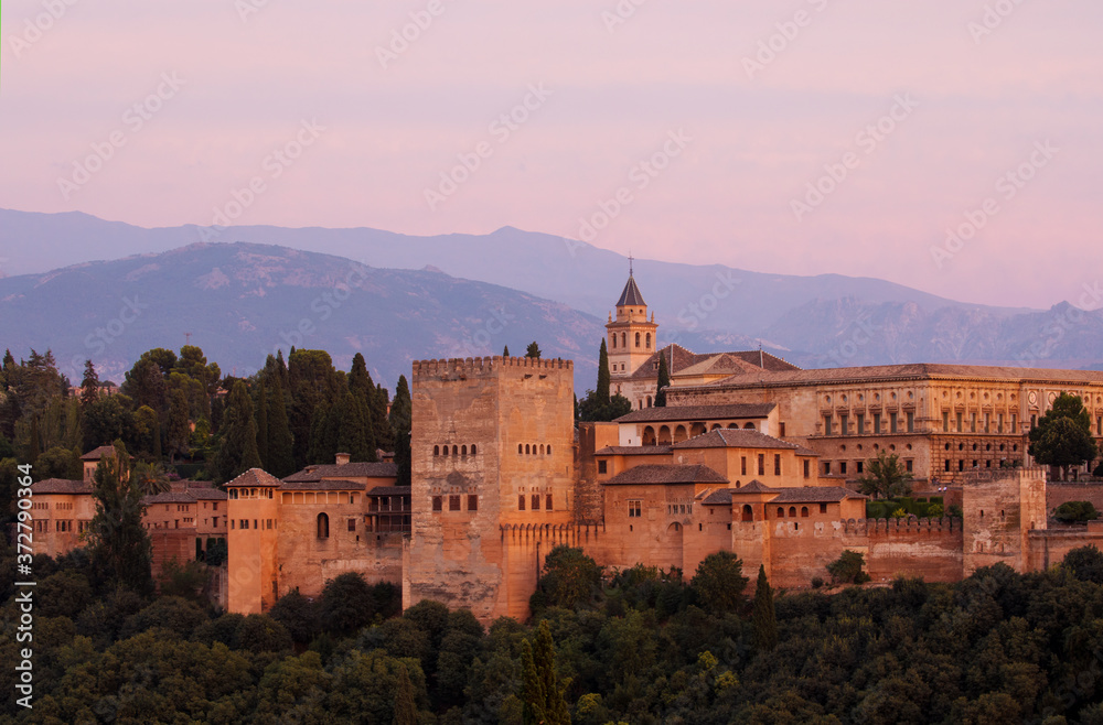The majestic Alhambra photographed at sunset with mountains in the background.
