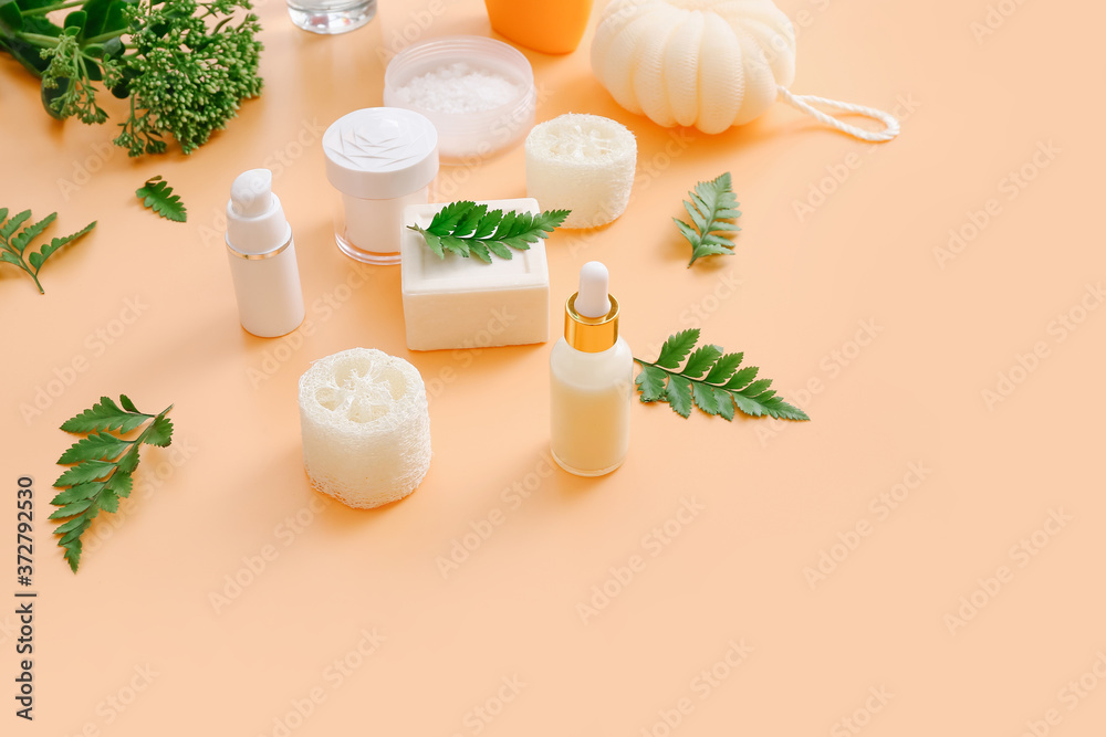 Bath accessories and natural cosmetics with green leaves on peach color background Bath accessories and natural cosmetics with green leaves on peach color background