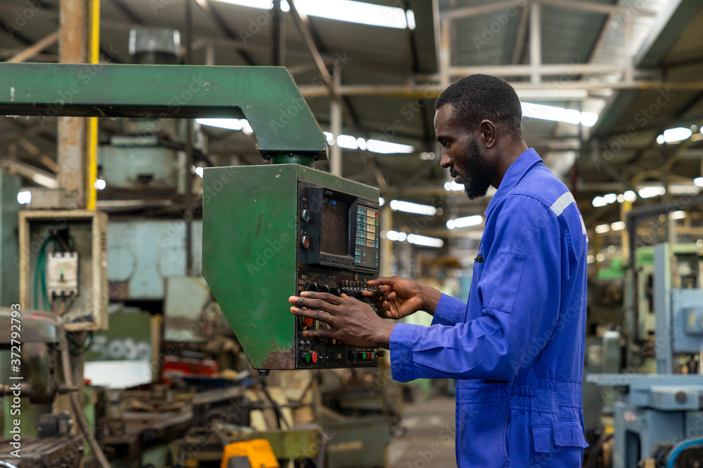 African american industry worker control machines in the workplace on a business day. 
Technician engineer checking and working in the factory. Concept of Industrial manufacturing.