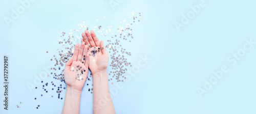 Hands with sparkling stars decorations on blue background. Stylish atmospheric image. Happy birthday concept. Holiday decor. Magic in hands. Christmas