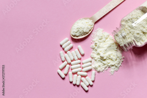 Dietary Supplement in powder and pills on a pink background. Top view  horizontally with space