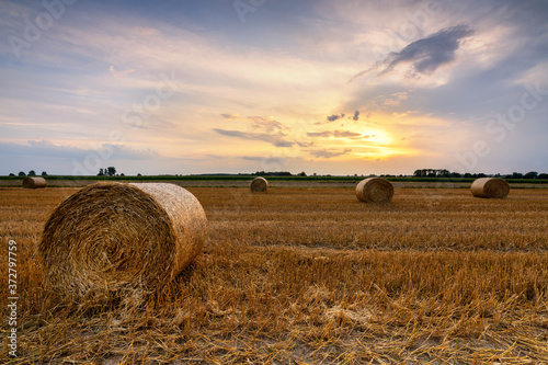 Beautiful summer sunrise over fields with hay bales