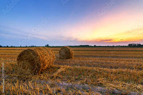 Beautiful summer sunrise over fields with hay bales photo