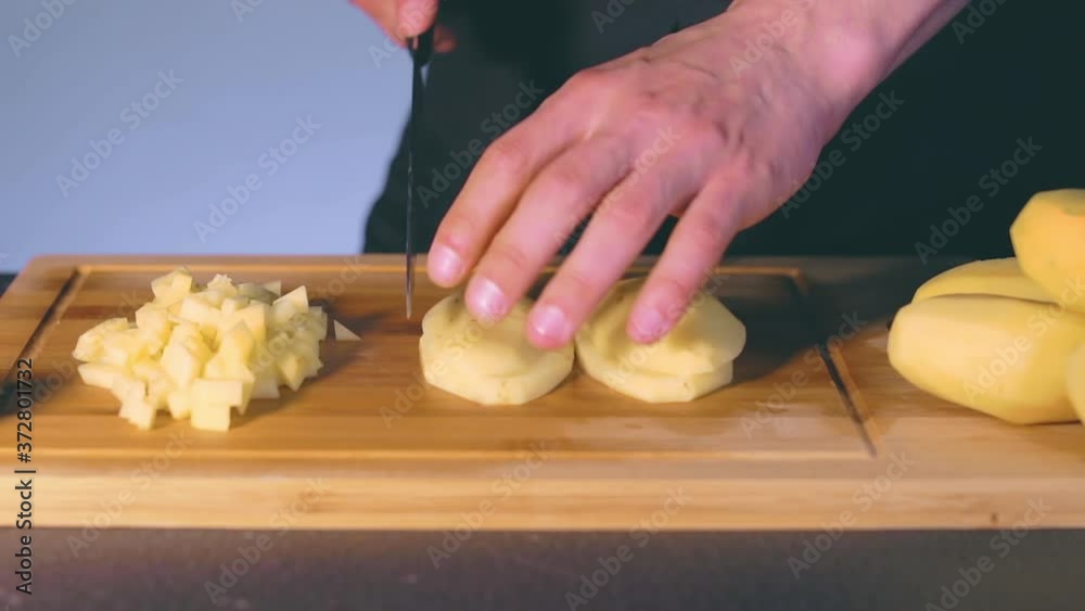 Chef in Black Uniform is Slicing Raw Potato. Man in a Kitchen is Cutting Potato and Preparing Ingredients for Cooking - Slow Motion. Static Shot Chef in Black Uniform is Slicing Raw Potato. Man in a Kitchen is Cutting Potato and Preparing Ingredients for Cooking - Slow Motion. Static Shot