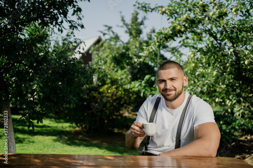 portrait of a young man. drink coffe in garden