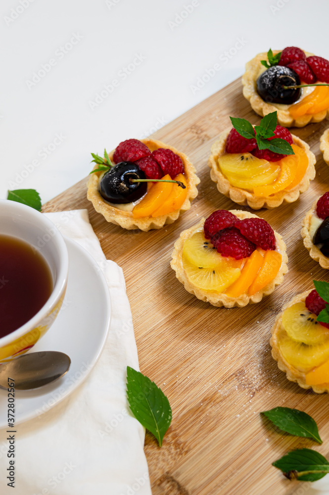 fruit tartlets being served with a cup of tea fruit tartlets being served with a cup of tea