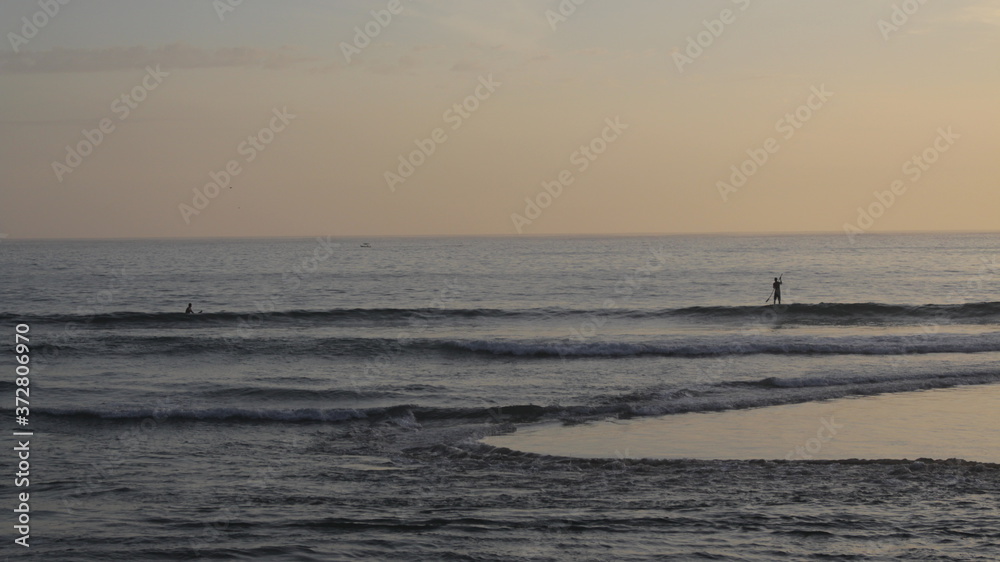 Calm water, people surfing, sunset beach in Paraty, Rio de Janeiro - Brazil.