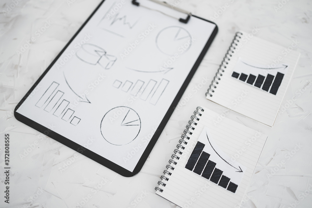 business analysis and statistics, positive and negative trends on graphs on notebooks next to clipboard with mixed charts business analysis and statistics, positive and negative trends on graphs on notebooks next to clipboard with mixed charts