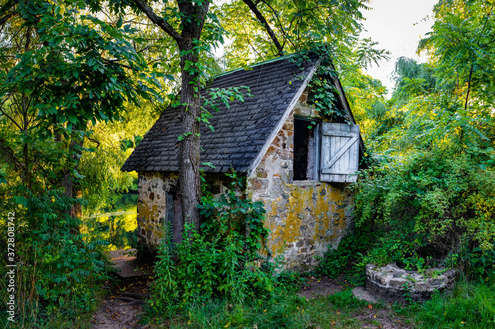 Peaceful abandoned old cottage at summer sunset in the woods