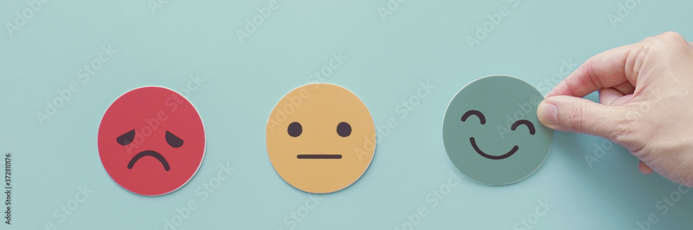 Hand choosing green happy smile face paper cut, feedback rating and positive customer review, experience, satisfaction survey ,mental health assessment, world mental health day, think positive concept Hand choosing green happy smile face paper cut, feedback rating and positive customer review, experience, satisfaction survey ,mental health assessment, world mental health day, think positive concept