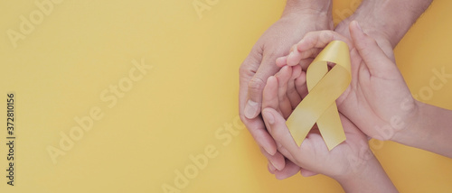 adult and child hands holding yellow gold ribbon, Sarcoma Awareness, Bone cancer, childhood cancer awareness, world suicide prevention day, September Yellow photo