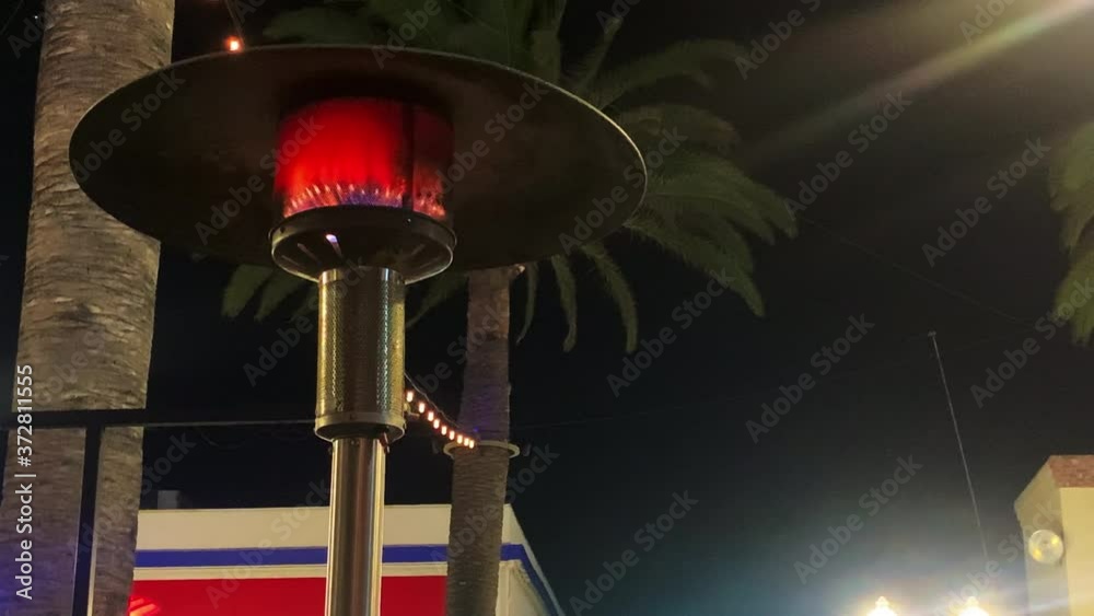 An ourdoor heater at full flame burns hot on the patio of a california resturant Wide Shot