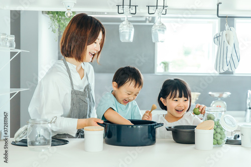 新築のリビングで母親が子供二人に料理を教えている　fmaily kids 子育て photo