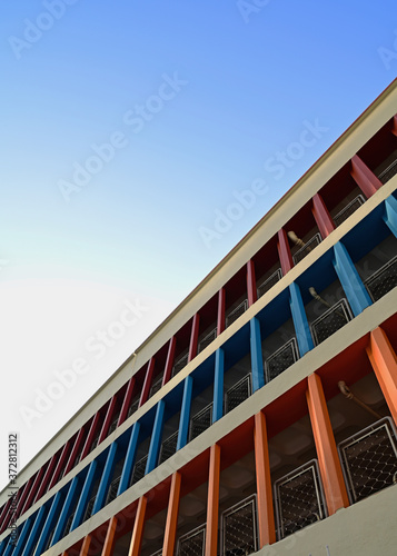 Singapore, 10 August 2020: An old multi-storey car park made in concrete with brutalist architecture and painted in a few colors. The background is a clear blue sky before sunset.