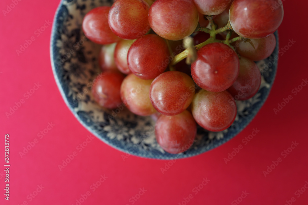 Directly Above View A Bowl Of Red Grapes Against Pink Background Directly Above View A Bowl Of Red Grapes Against Pink Background