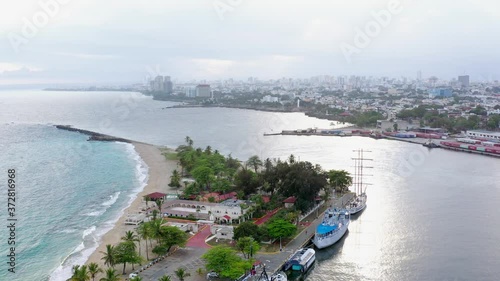 Flying Over Calm Caribbean Sea at Playa Punta Torrecillas Beach with Santo Dominigo in the Background, Aerial Circle Orbit Drone Shot photo