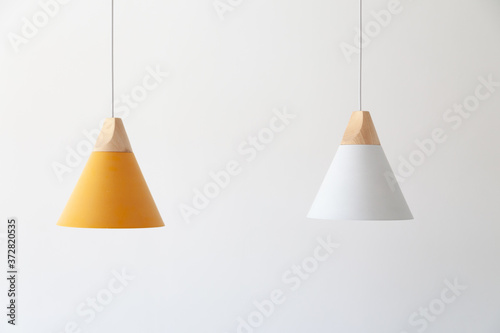 White and yellow lamps with light wooden parts are hanging on the cables photo