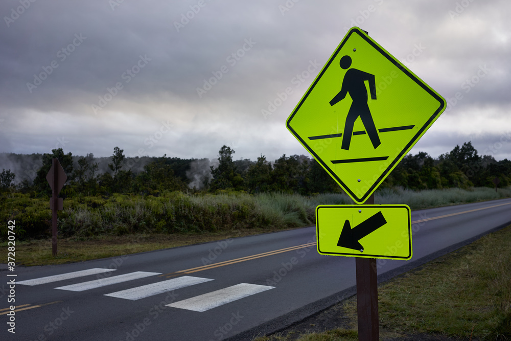 Pedestrian crossing sign on a park road at dawn or dusk. Pedestrian crossing sign on a park road at dawn or dusk.