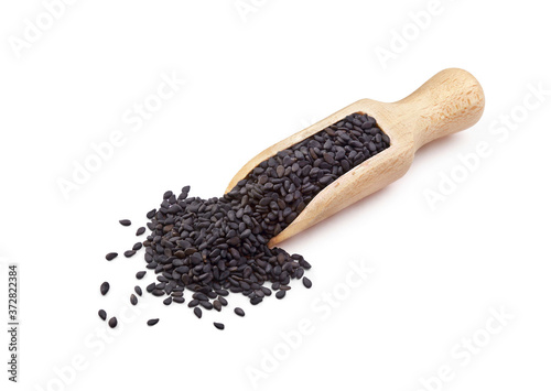 Black sesame seeds in wooden scoop isolated on white background