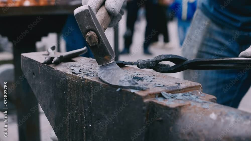 Blacksmith tapping metal detail with a hammer Blacksmith tapping metal detail with a hammer