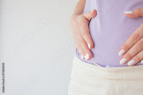 Pregnant woman in the early stages touches the belly with her hands. First and second trimester of pregnancy
