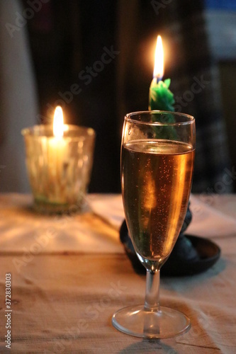 A glass of champagne and two candles in the background