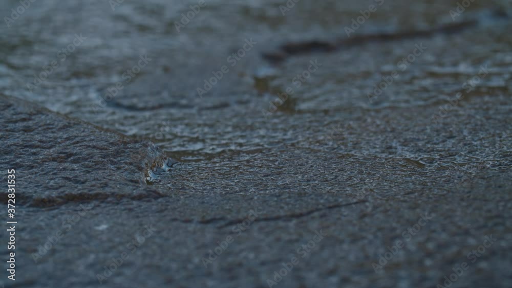 Textured wet black stone surface close-up. Black flat stone background. Macro shooting, camera slowly moving on slider. Textured wet black stone surface close-up. Black flat stone background. Macro shooting, camera slowly moving on slider.