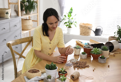 Mature woman potting plant at home. Engaging hobby