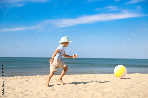 Cute little boy playing with inflatable ball on sandy beach