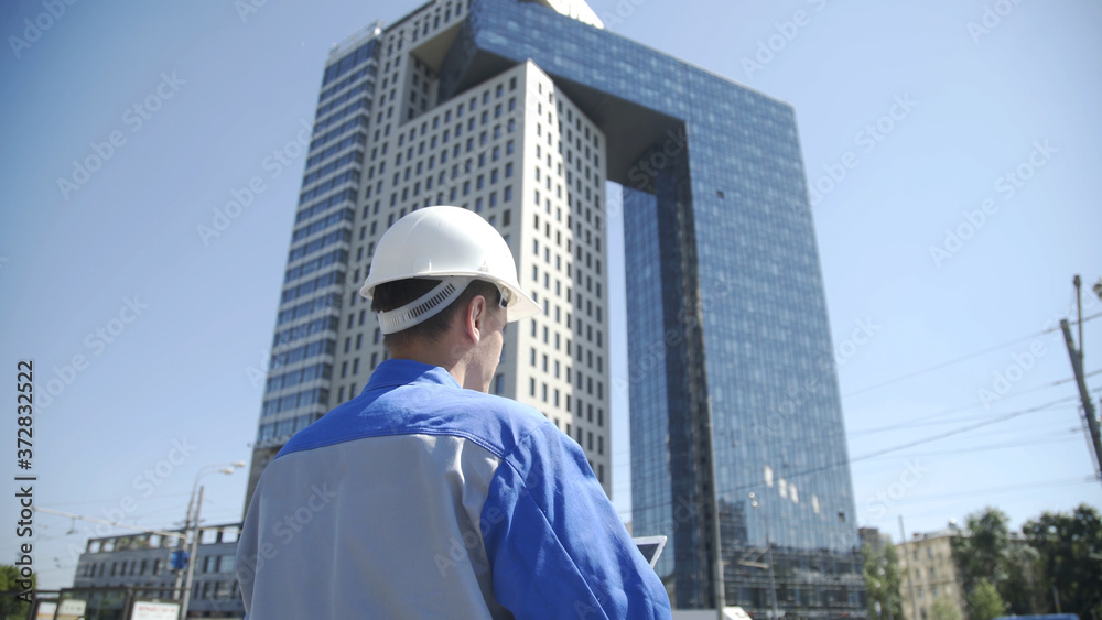 Portrait of a successful young handsome engineer, architect, builder, businessman, wearing a white helmet, holding a tablet with project in his hand Portrait of a successful young handsome engineer, architect, builder, businessman, wearing a white helmet, holding a tablet with project in his hand