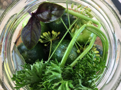 Top view of a glass jar with cucumbers and herbs photo