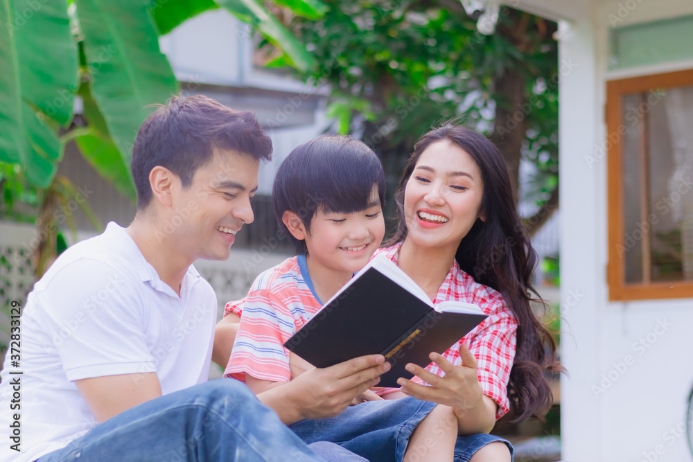 Happy family reading book as activity together in yard at home Happy family reading book as activity together in yard at home