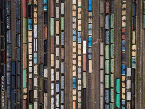 Cargo trains close-up. Aerial view of colorful freight trains on the railway station. Wagons with goods on railroad. Heavy industry. Industrial conceptual scene with trains.