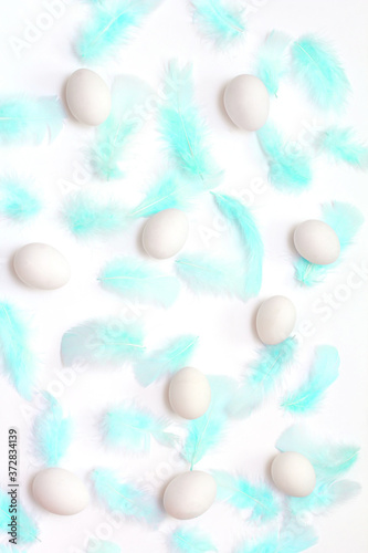 light turquoise feathers and eggs on a white background. minimalistic easter composition. flat lay, top view
