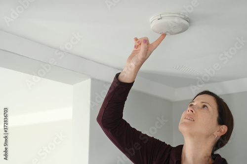 Young adult woman checking fire alarm