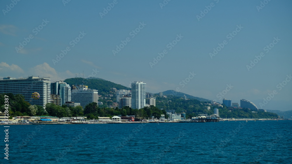 Panorama of the coast of Sochi in summer. Large-format. Black Sea, Russia. View from the sea. No people. Sunny day. Modern city on the beach. Panorama of the coast of Sochi in summer. Large-format. Black Sea, Russia. View from the sea. No people. Sunny day. Modern city on the beach.