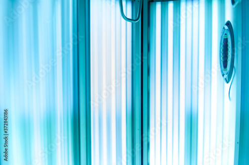 Vertical Tanning turbo Solarium Light Machine with glowing blue light ultraviolet lamps for tanning and skin care. Empty tanning Modern solarium, inside. Horizontal photo
