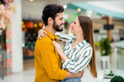 Profile side photo of positive gentle cute spouses girl husband hug cuddle enjoy valentine day rest relax wear yellow striped shirt in shopping mall center store