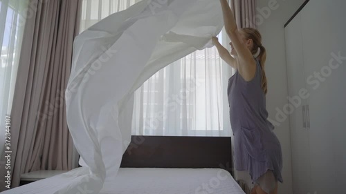 Slow-motion shot of a young woman changes bed linen in a room photo